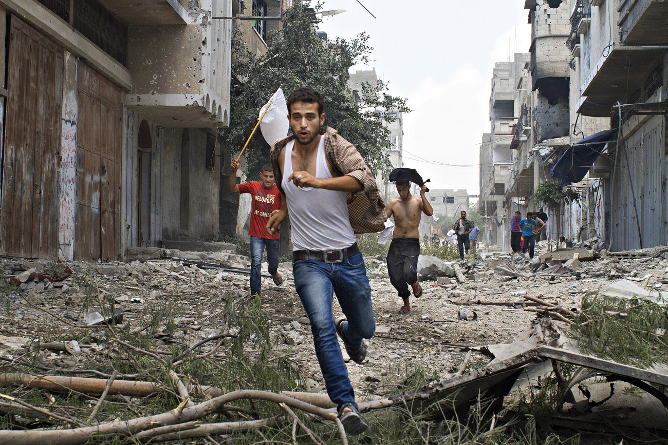 Palesztin férfiak menekülnek az izraeli katonák elől Shejaia városban