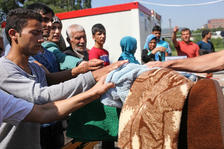 Pokrócot osztanak a menekülteknek a Nyugati pályaudvari tranzitzónában (Fotó: Hernád Géza)