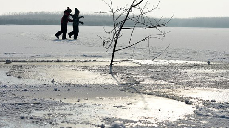 Gyerekek játszanak a befagyott Tisza-tavon Sarudnál 2016. január 23-án. Elöl faág figyelmeztet a veszélyre egy léknél. MTI Fotó: Mészáros János