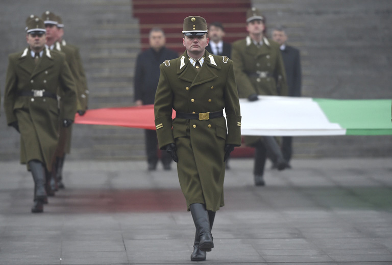 katonai tiszteletadással felvonják, majd félárbócra eresztik a nemzeti lobogót