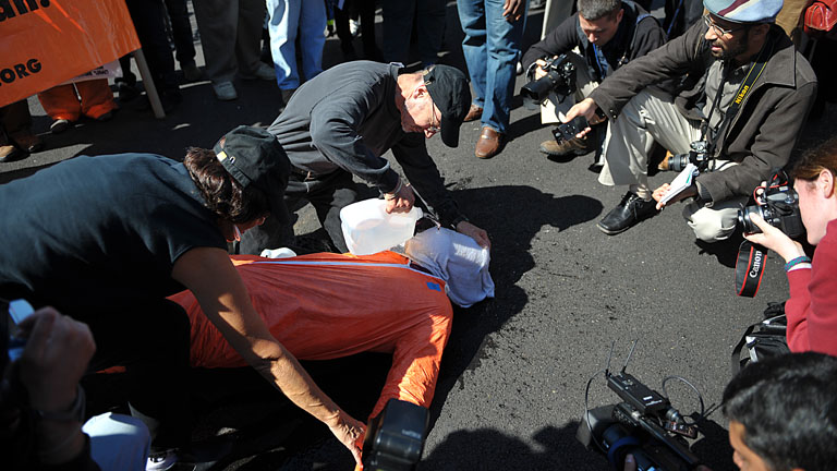 Békepárti tüntetők egy önkéntes bevonásával demonstrálják a waterboarding nevű kínzási módszert