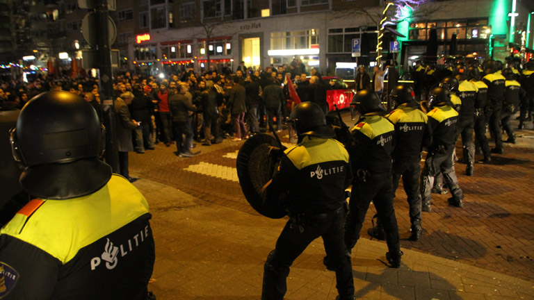 A holland rohamrendőrök farkasszemet néznek a török tüntetőkkel Rotterdamban, március 12-én. 