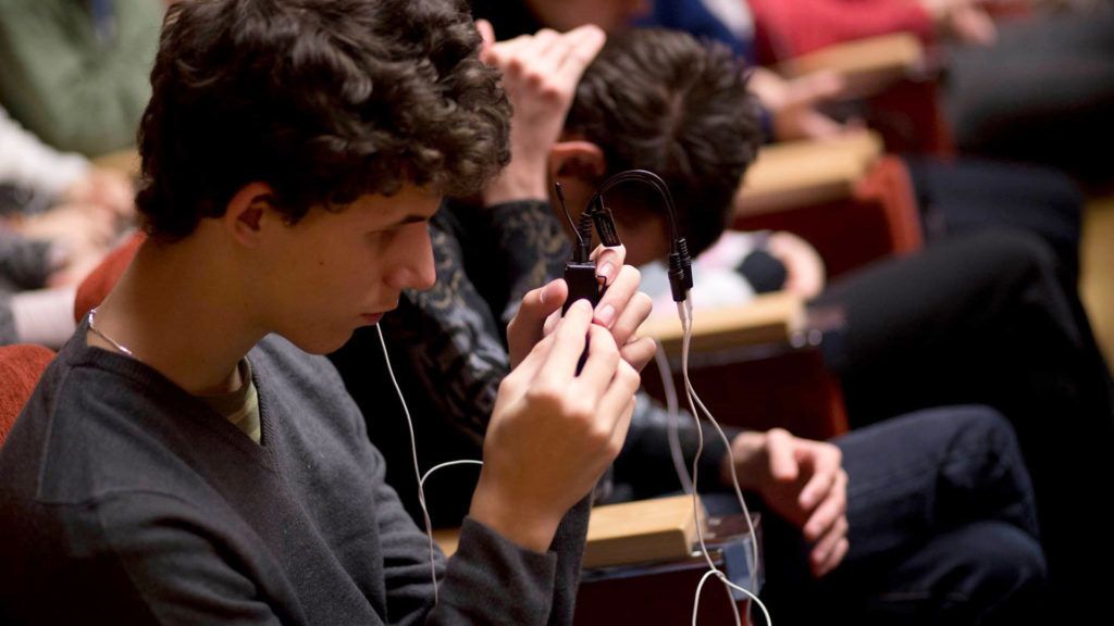 Egy néző az audionarráció követéséhez szükséges eszközt tartja maga előtt Az Esőkirály és a szépséges Jázminvirág c. darab előadásán (Fotó: Todoroff Lázár/AKKU)