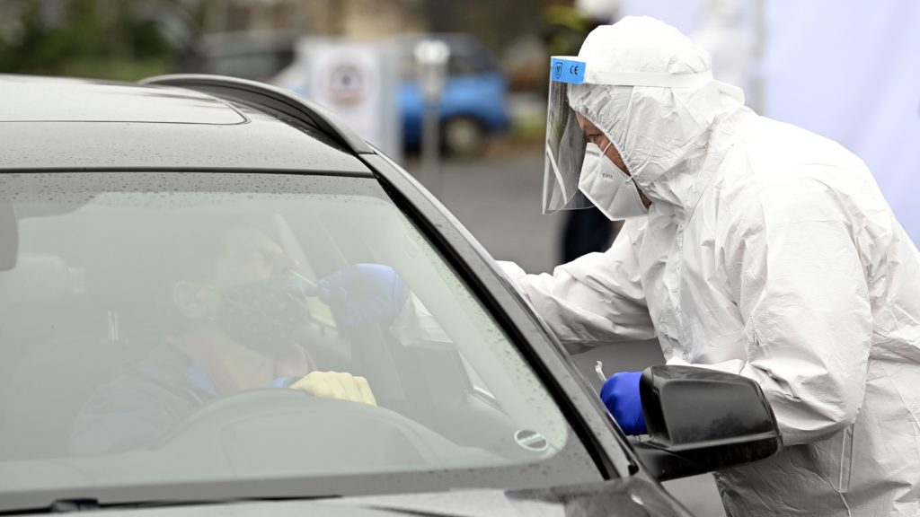 Mintát vesznek egy autóval érkező pácienstől a koronavírus-gyanús esetek szűrésére felállított mobil mintavételező állomáson.