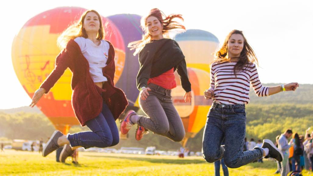 boldog nők ugranak színes hőlégballonok előtt