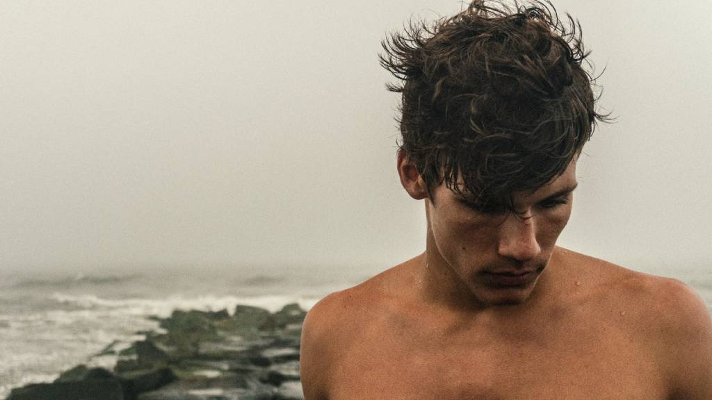 szomorkás félmeztelen férfi tengernél