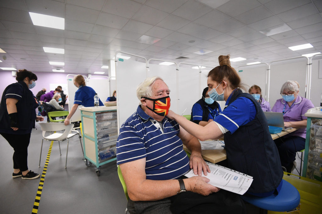 Koronavírus elleni oltóanyagot adnak be egy férfinak az angliai Hertfordshire megyei Stevenage város konferenciaközpontjában létesített oltóközpontban 2021. január 11-én.