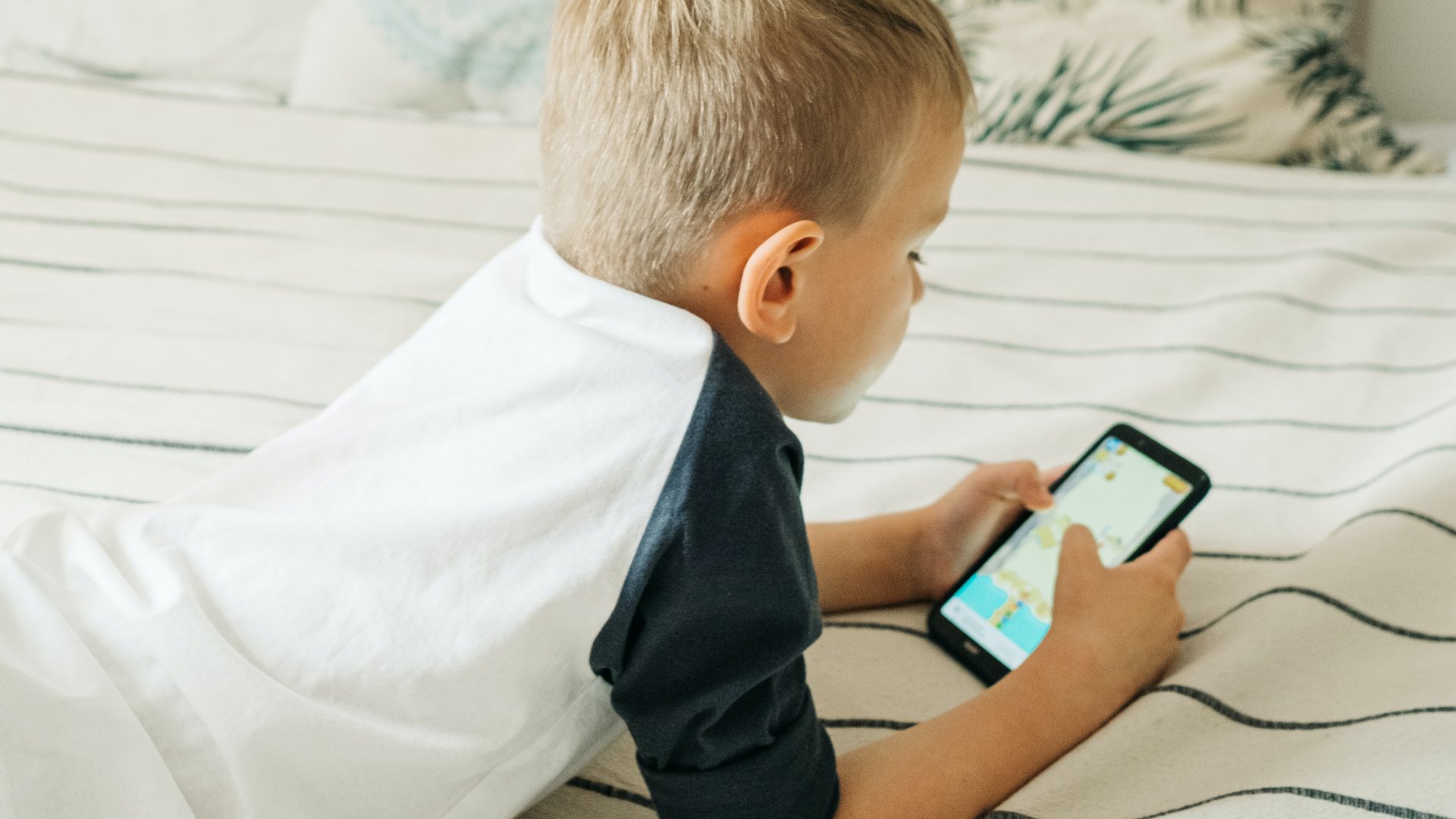 Mobiltelefonos játékkal játszik egy kisfiú