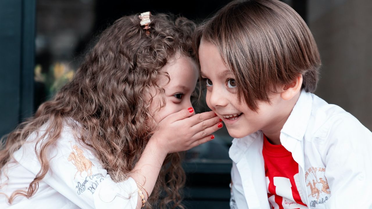 Kislány és kisfiú sugdolóznak