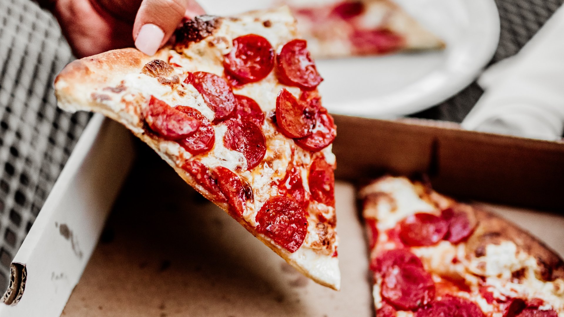 Egy szelet pizzát vesz ki a dobozból