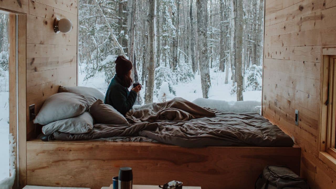 Nő az ágyban ül téli tájjal