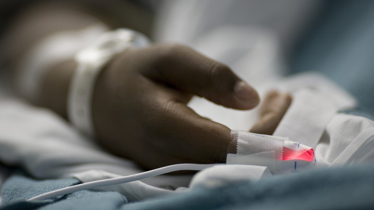 Egy férfi kéz a kórházi ágyon.