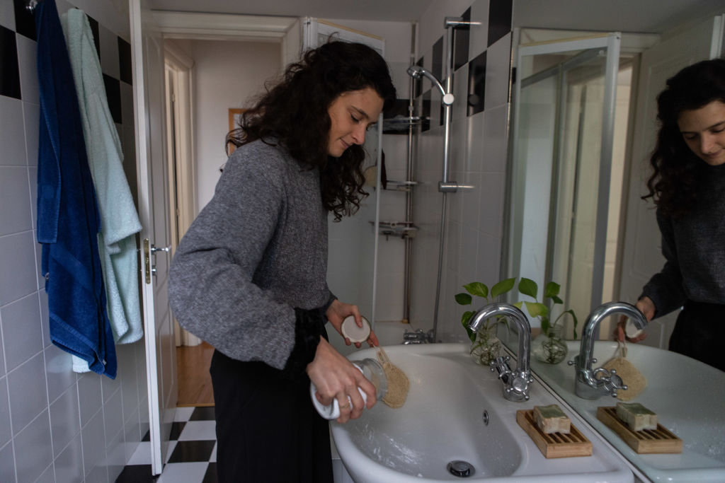 Egy nő szódabikarbónával mossa ki a mosdót.