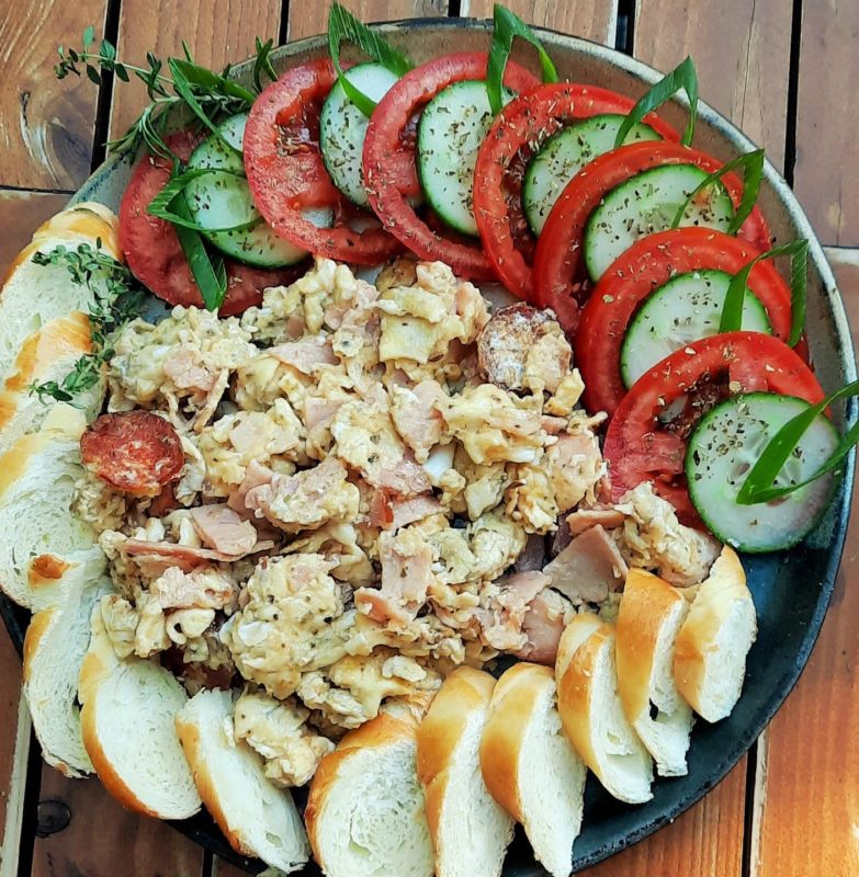 Sonkás-kolbászos rántotta bagett-, paradicsom- és kígyóuborka-koszorúban