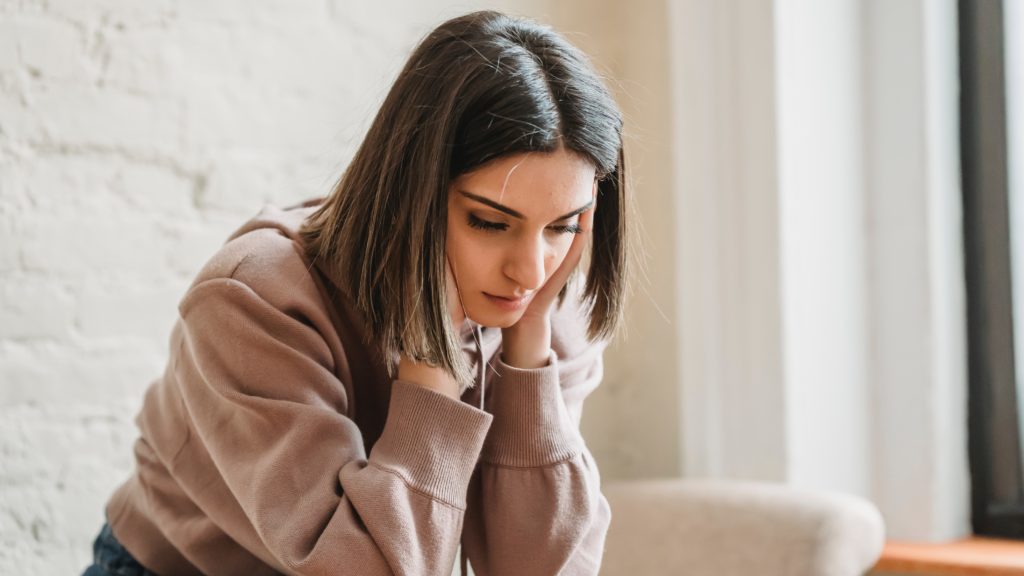 Szomorú nő ül a kanapén