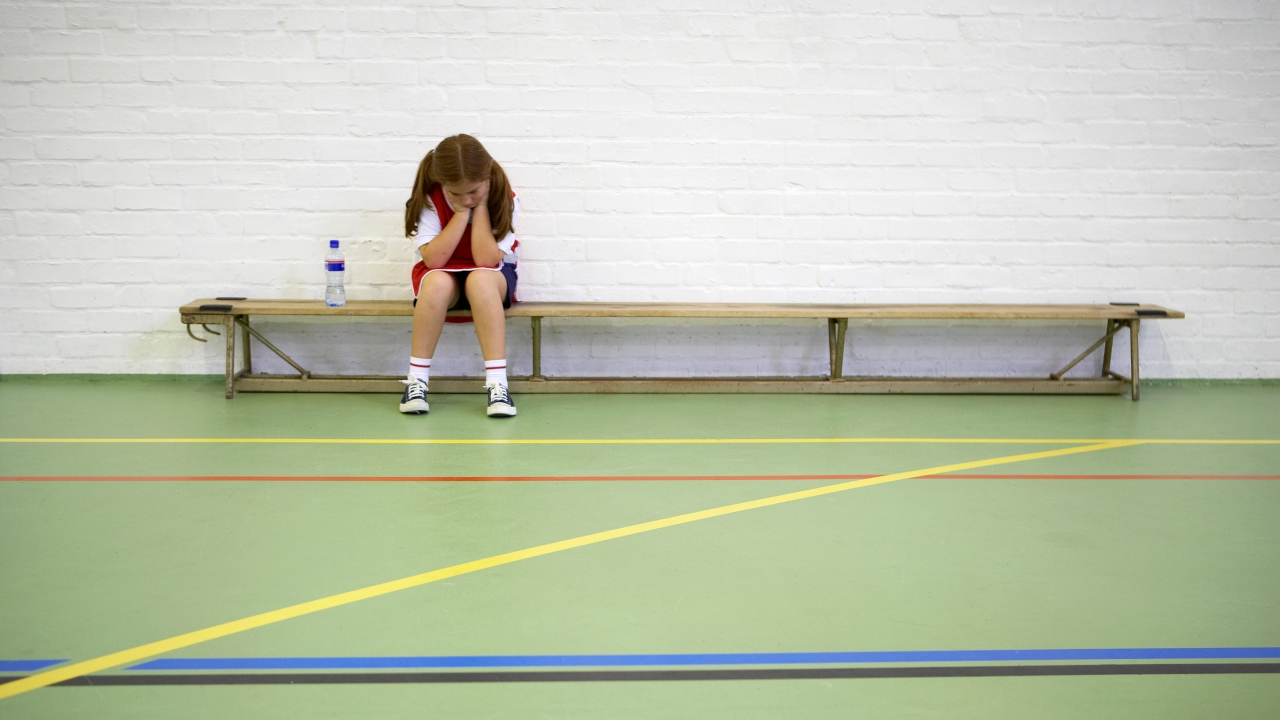 Szomorú kislány ül a tornateremben