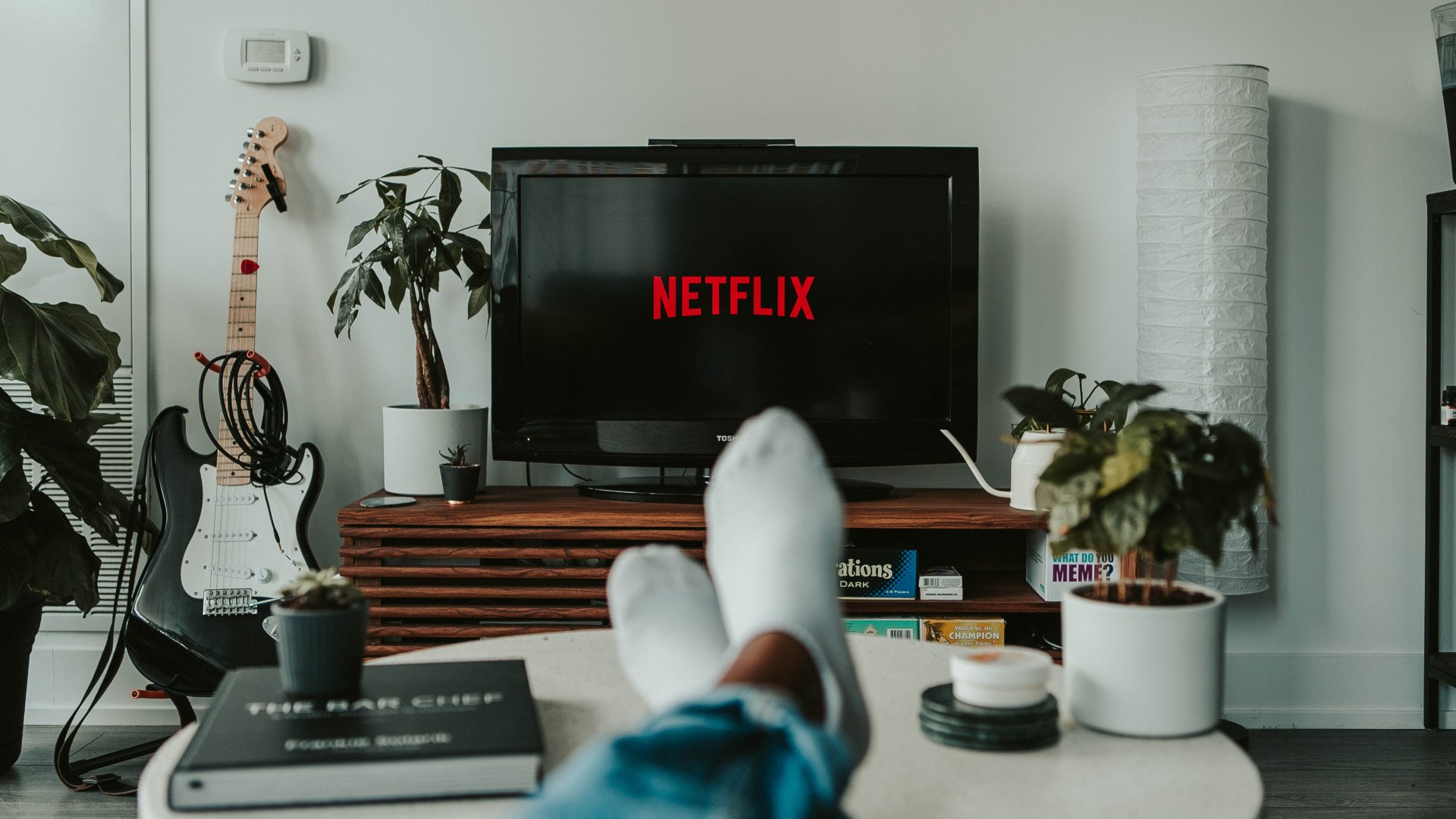 Asztalra feltett lábakkal nézi a Netflixet egy férfi