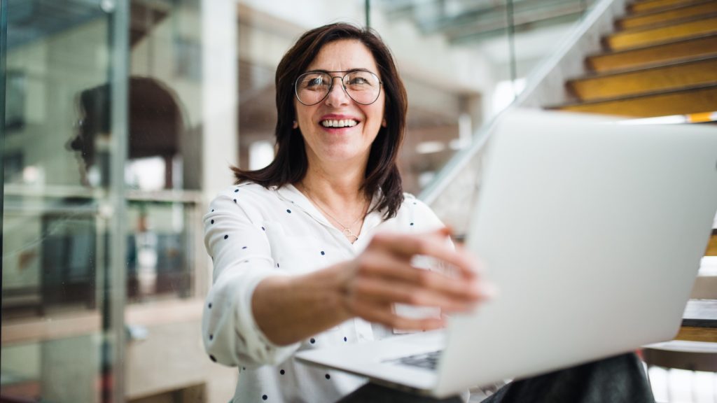 Egy nő laptoppal mosolyog