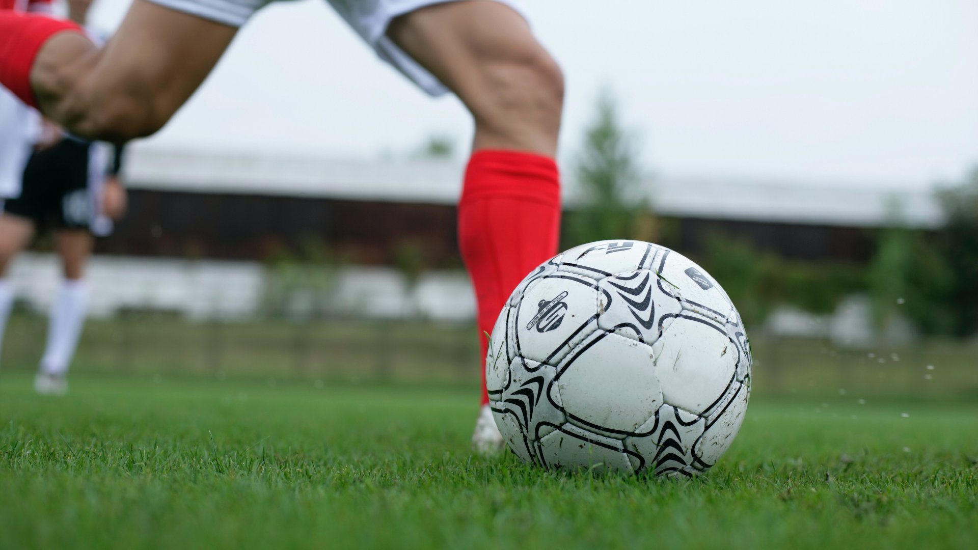 Egy piros sportszáras focista készül elrúgni a focilabdát