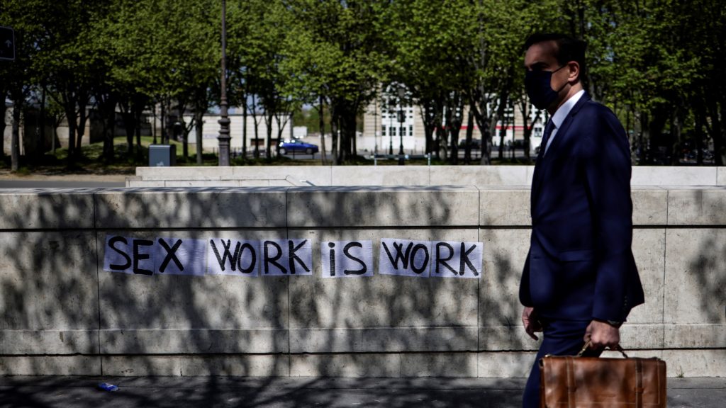 A szexmunka is munka jelentésű falfirka mellett sétál el egy férfi a francia szexmunkások tüntetésén, amelyet az ügyfeleik büntethetőségéről szóló törvényjavaslat elfogadásának ötödik évfordulóján tartanak Párizsban 2021. április 13-án