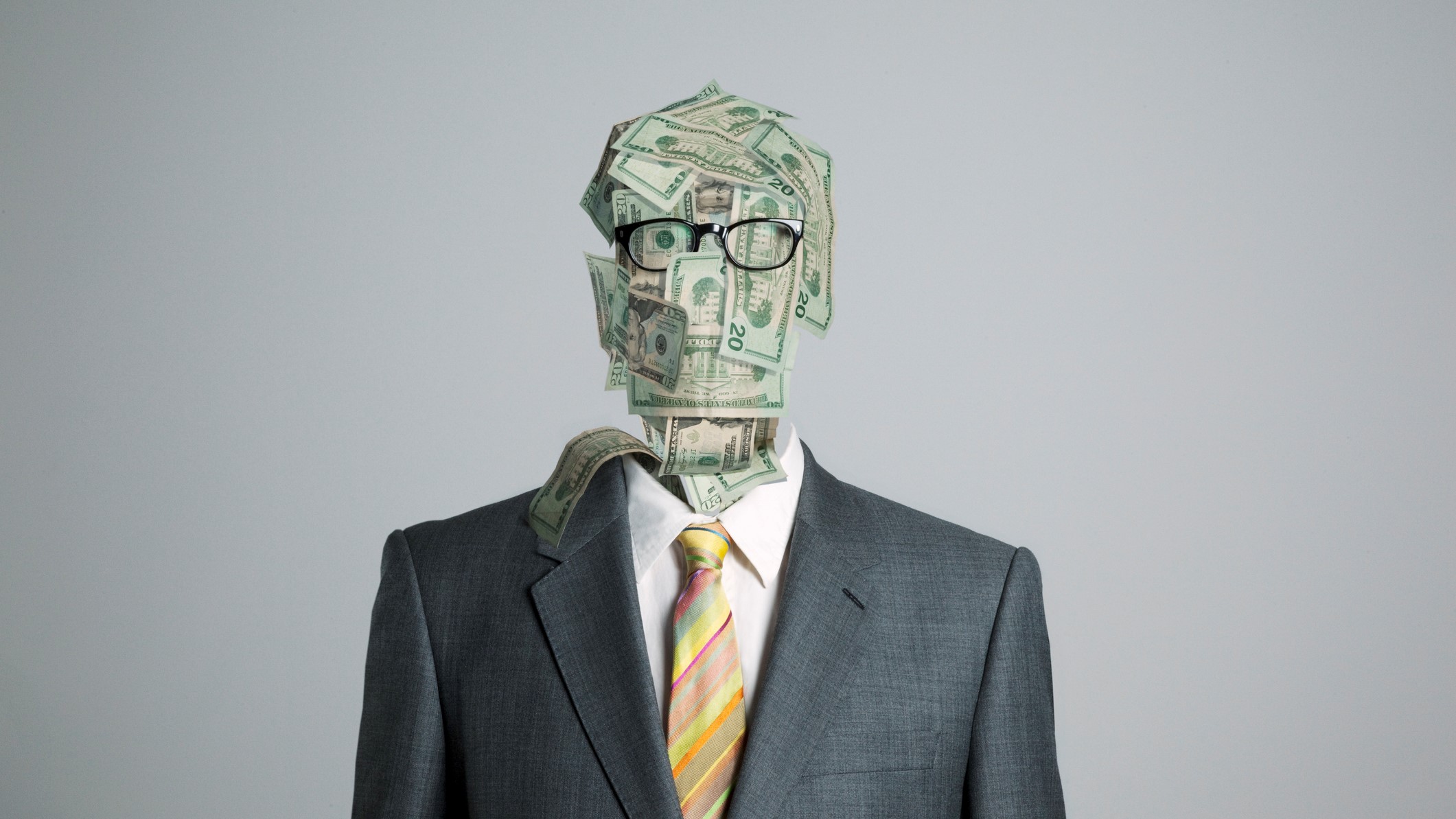 Öltönyös ember bankjegyekből álló fejjel