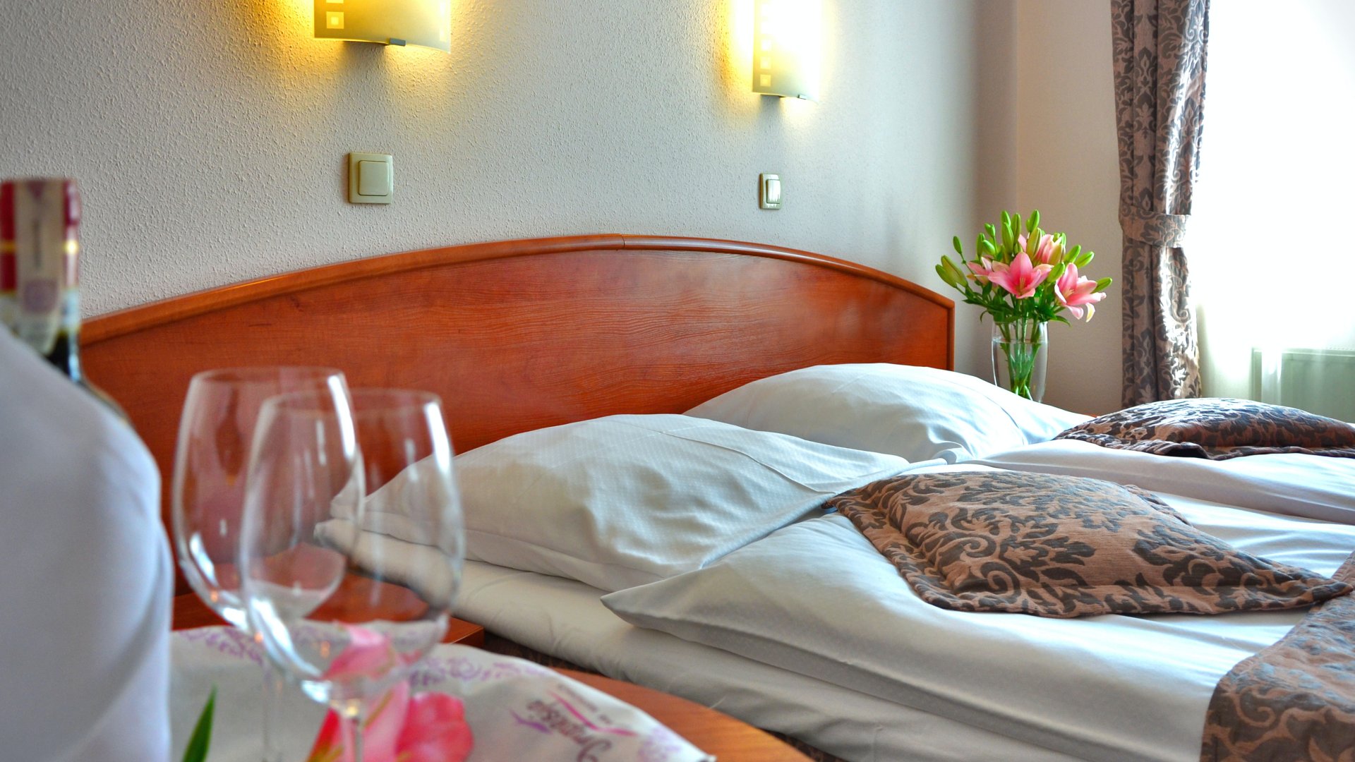 Ágy egy hotelben előtérben két boros pohár