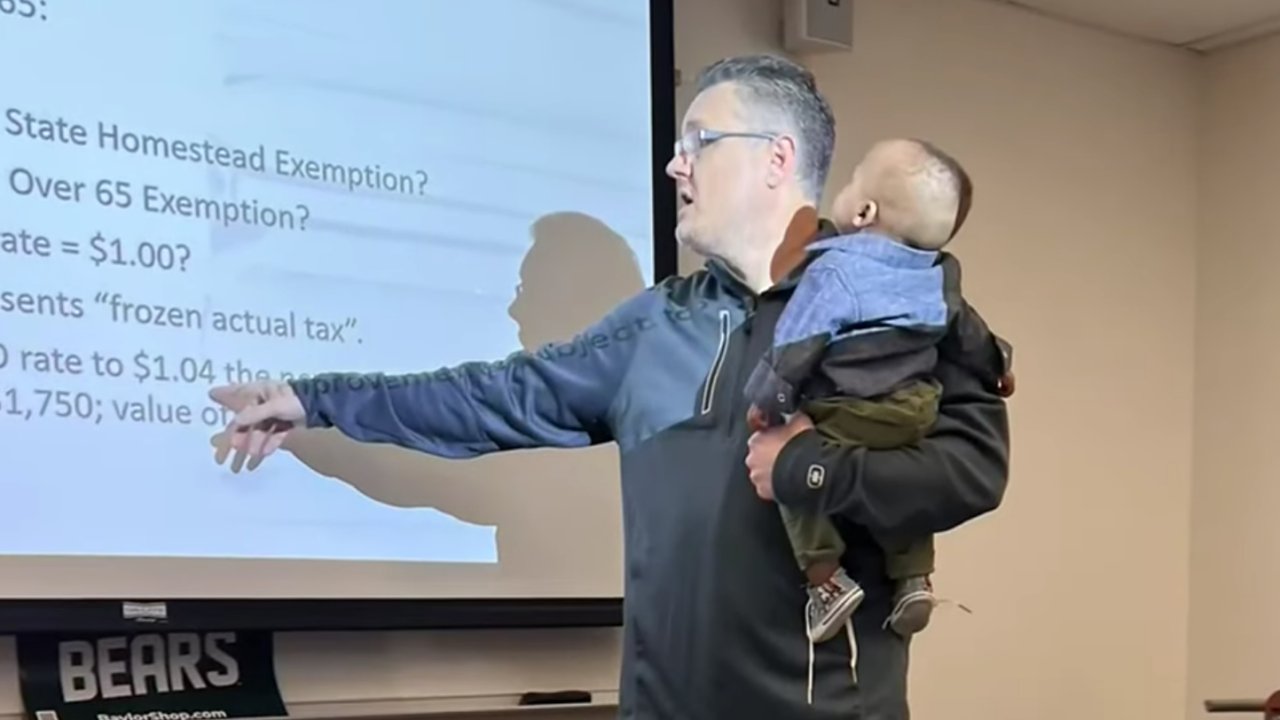 Bobby Ott, a Baylor Egyetem oktatója egyik tanítványa gyerekét fogja előadás közben
