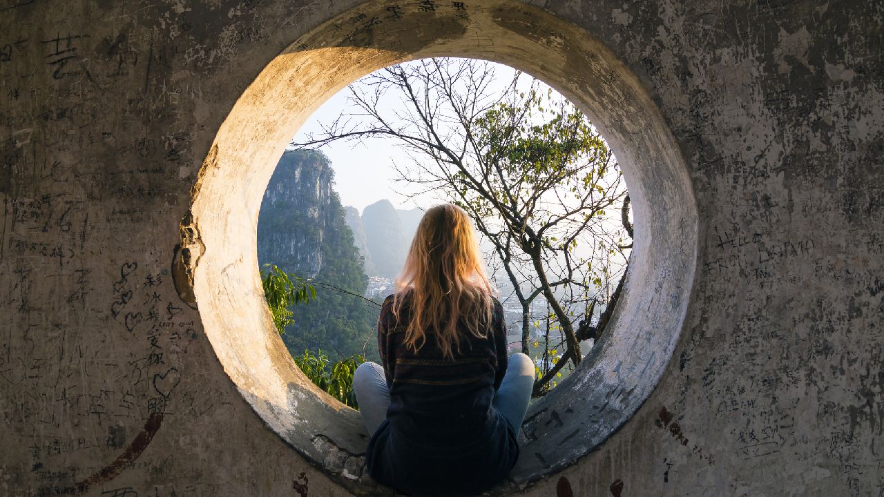 Nő ül a tájat nézve