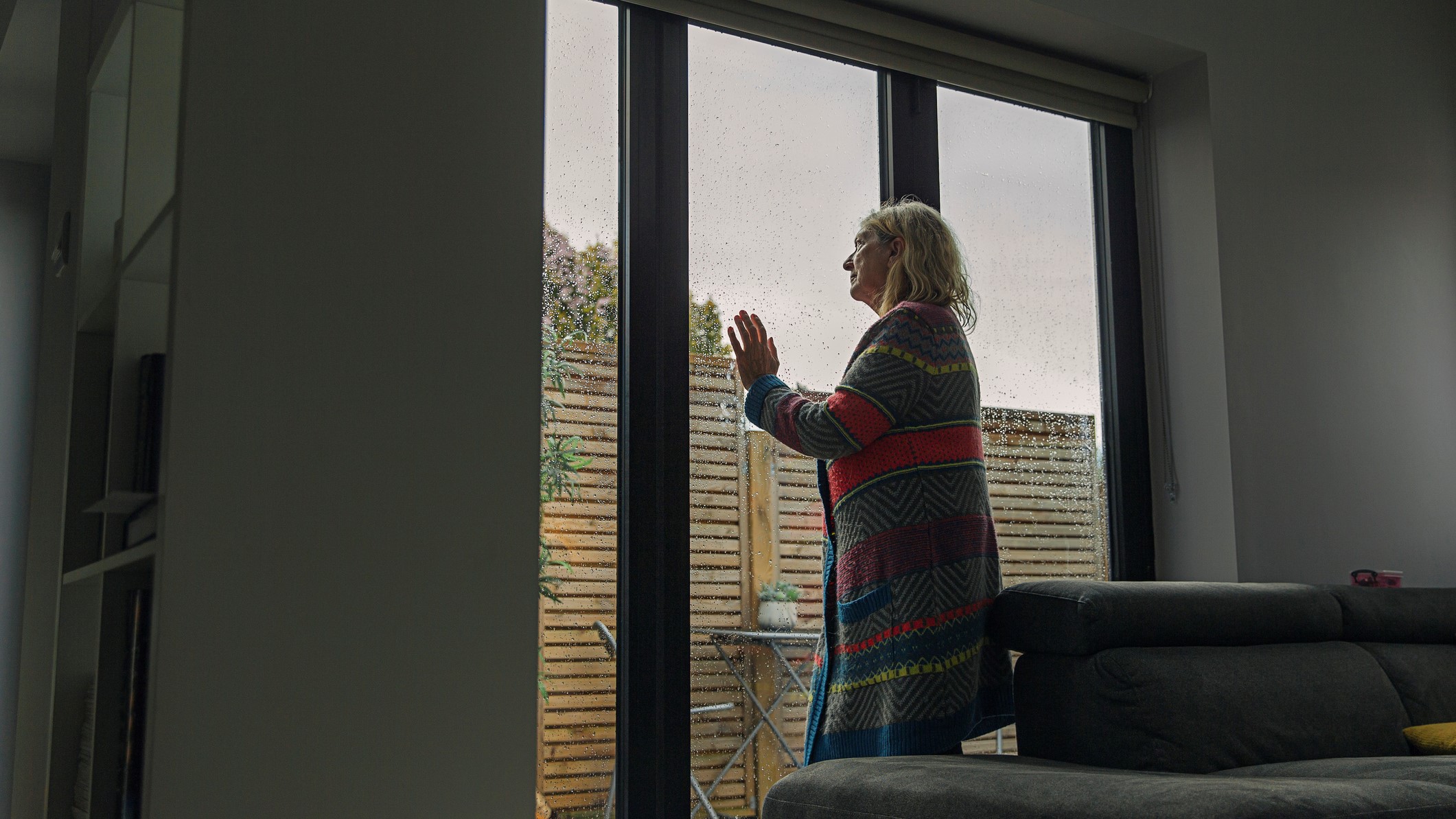 Idős nő kinéz az ablakon