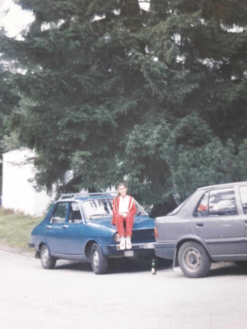 Kislány ül a kék Dacai motorháztetőjén