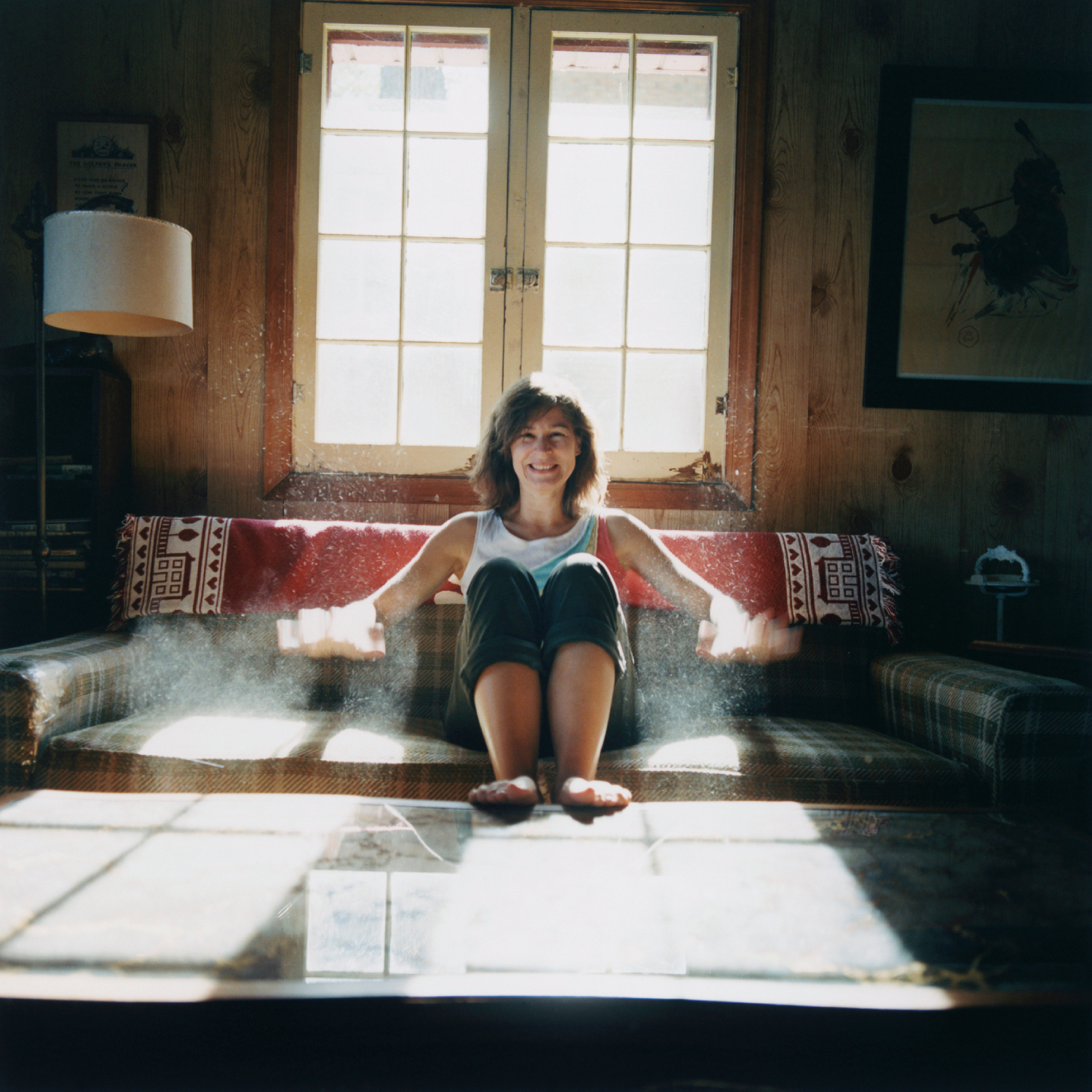 Poros kanapén ülő mosolygó nő.