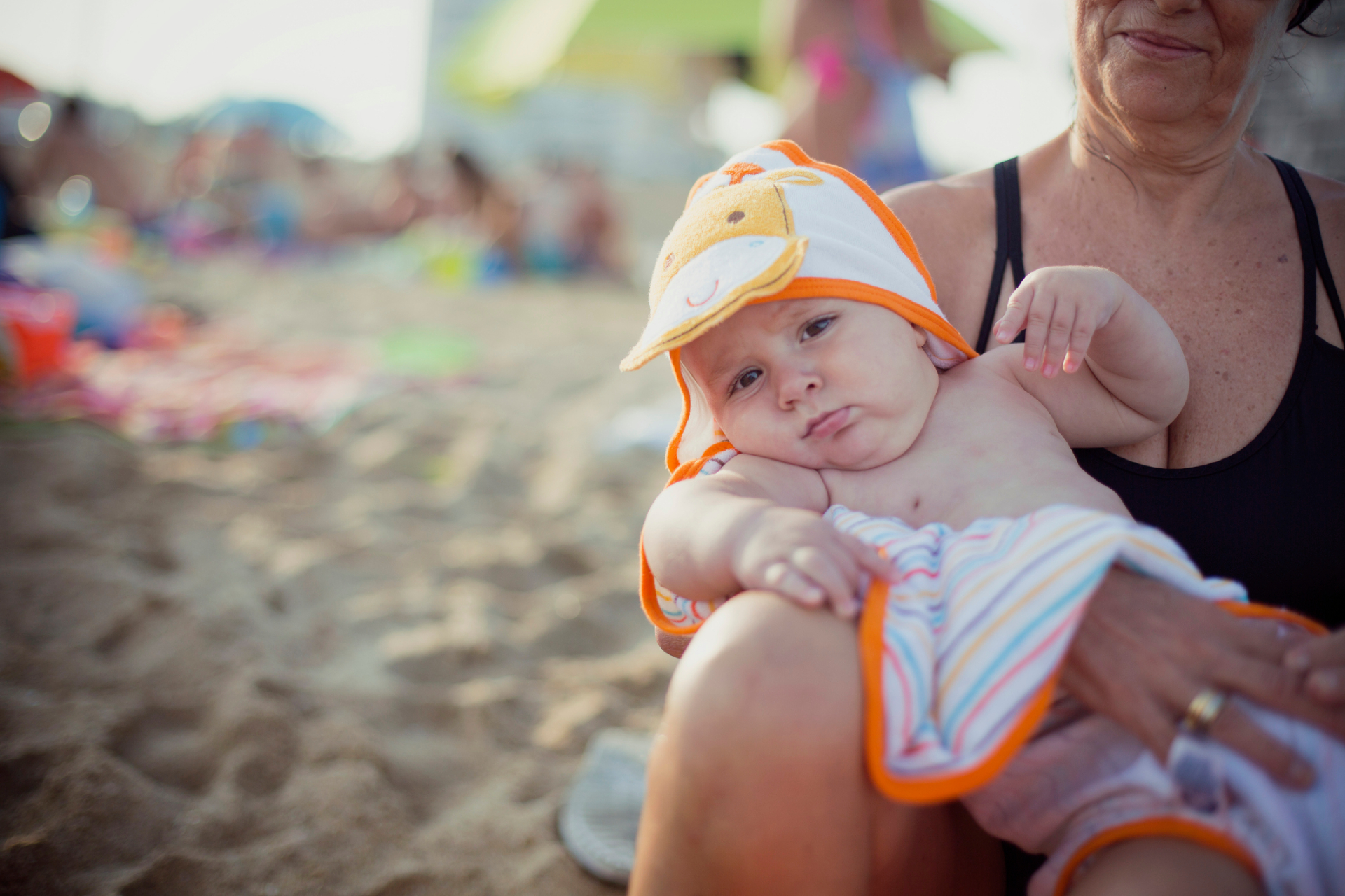 Kisbaba kapucnis törülközőben, egy nő ölében.
