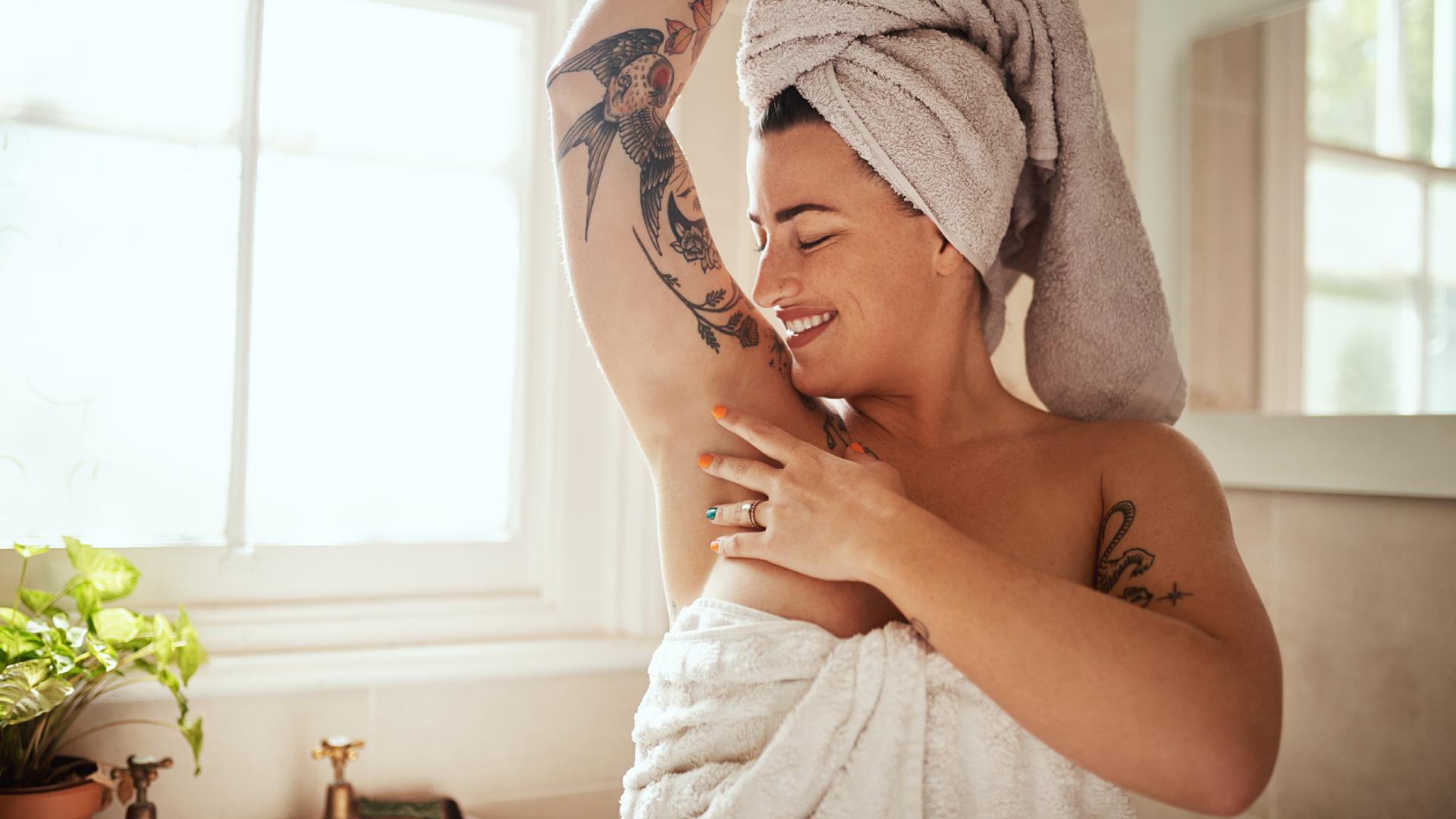 Törülközőbe csavart hajú nő boldogan simogatja a hónalját,