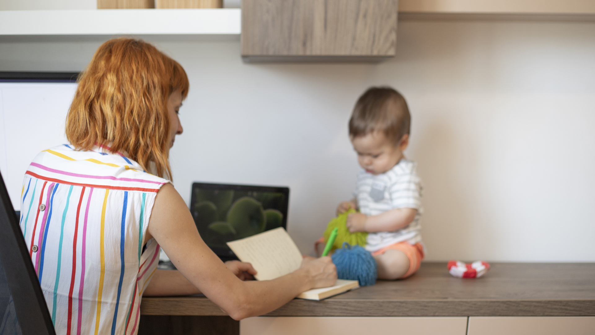 Egy fiatal anya otthonról dolgozik, miközben babájával is foglalkozik. 