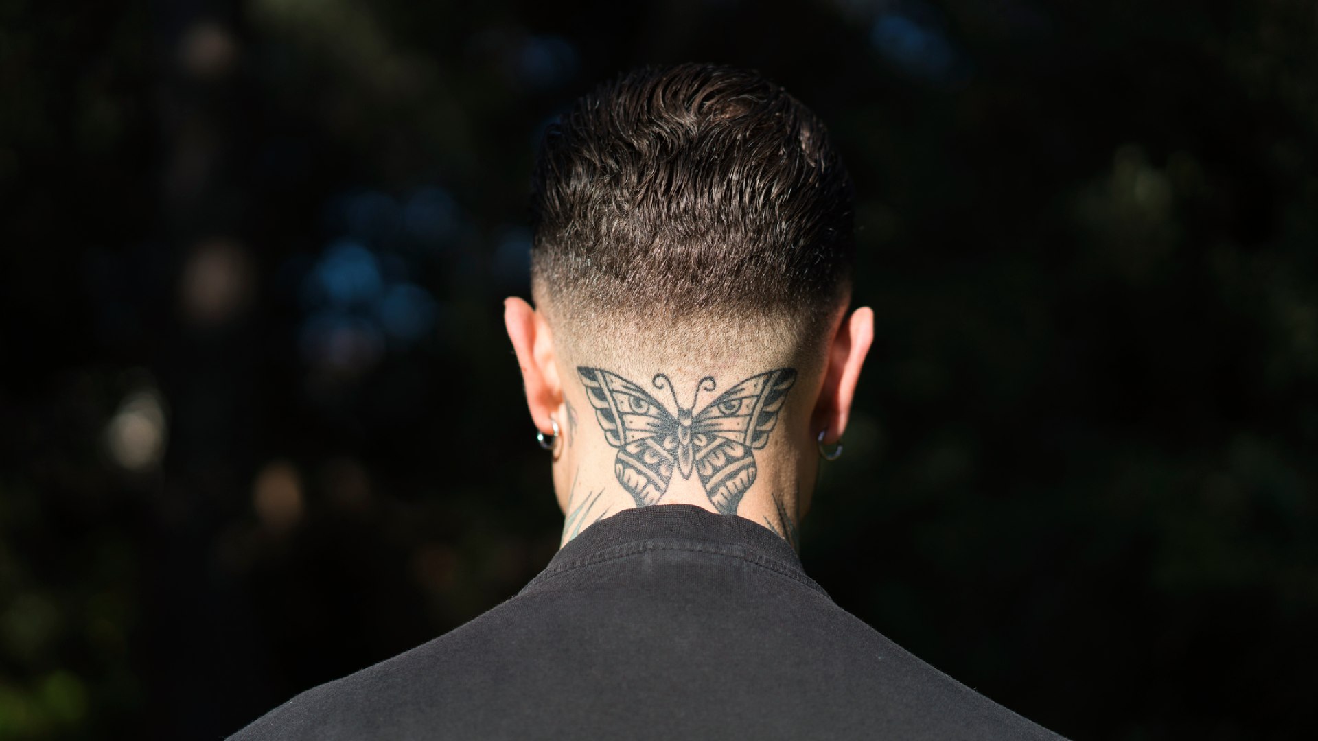 Férfi tarkóján pillangós tetkó.