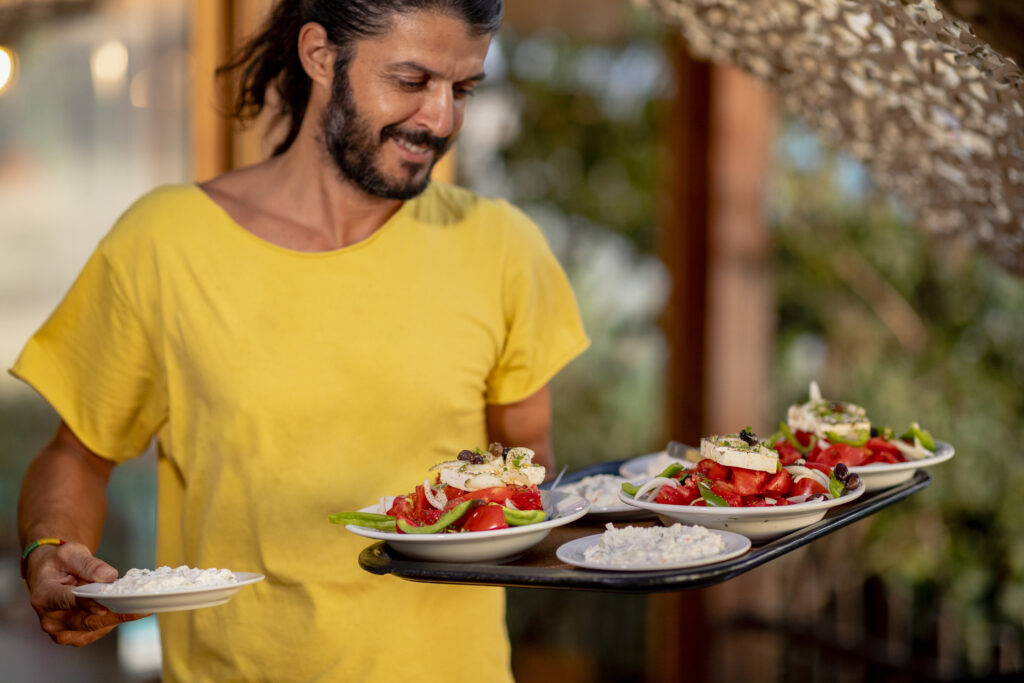 Görög pincér Krétán előételeket, köztük tzatzikit szolgál fel
