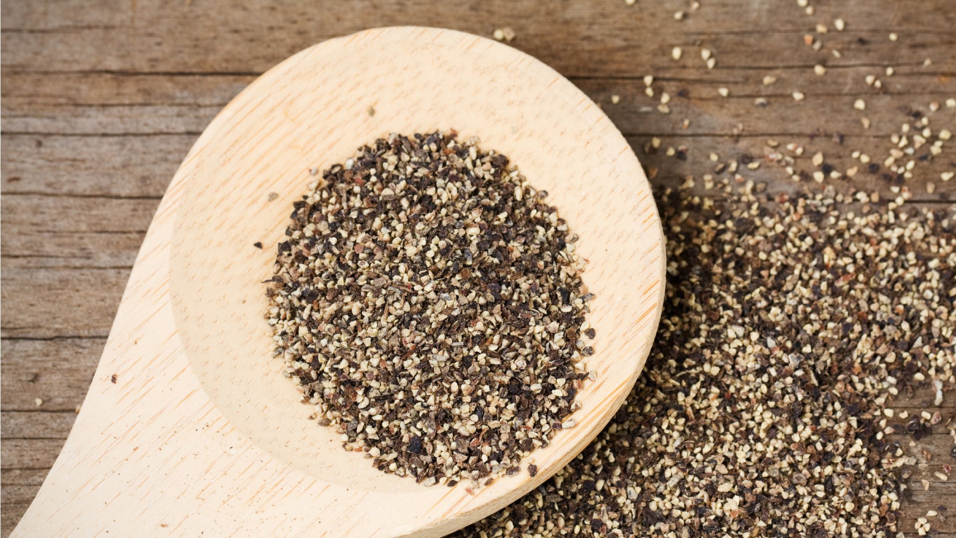 Őrölt bors fakanálon és asztalon.