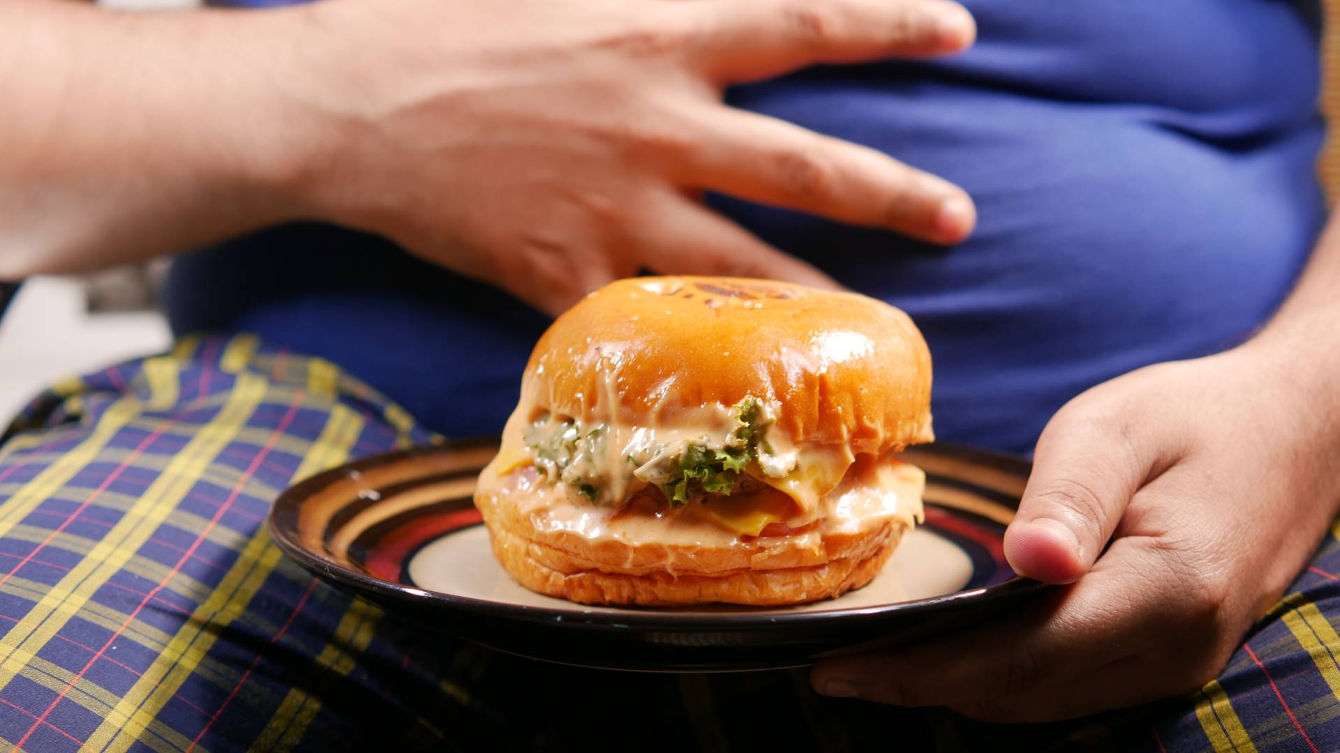 Hamburgert tartó, fájó hasú ember.