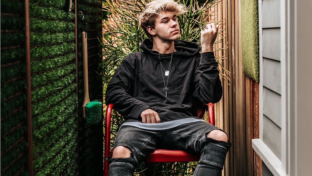 Kamasz fiú kertben ül