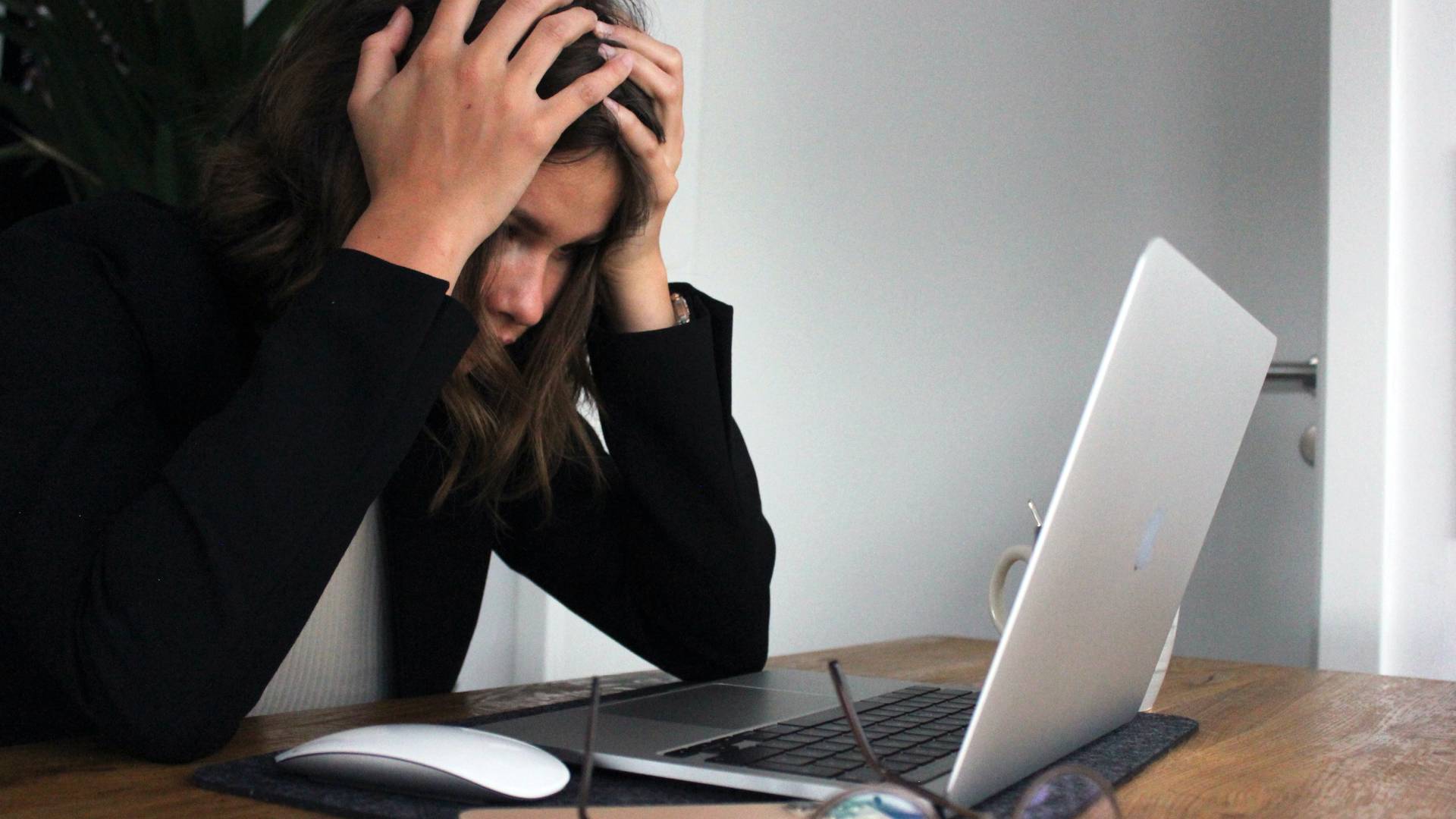 Laptopja előtt ülő stesszes nő.