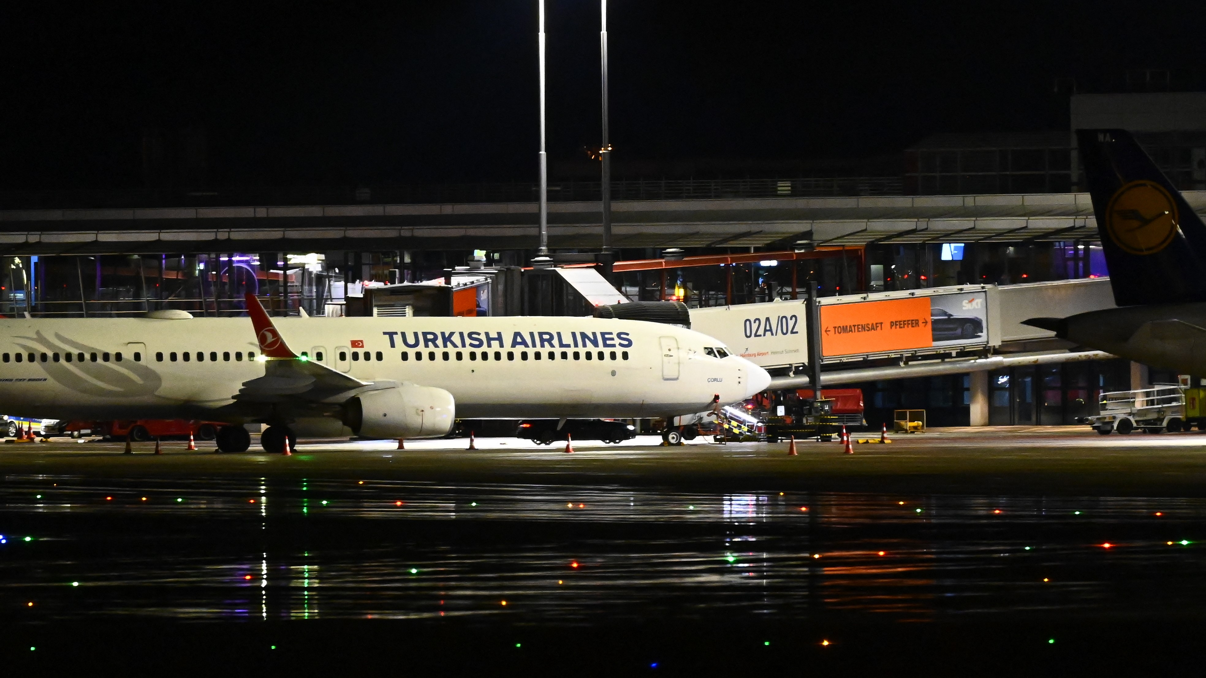 Egy sötét színű autó a Turkish Airlines repülőgépe alatt parkol a hamburgi repülőtéren