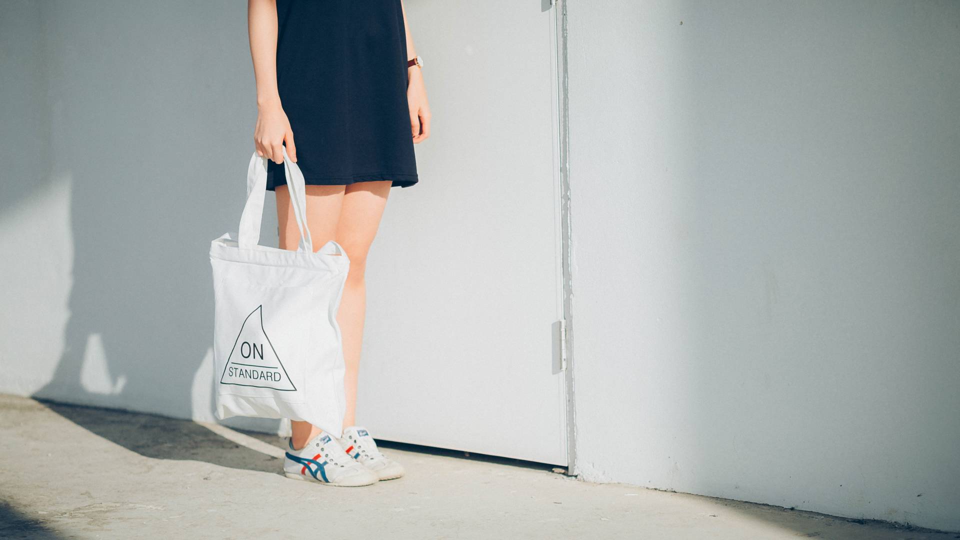 Kék szoknyás lány kezében fehér vászontáska.