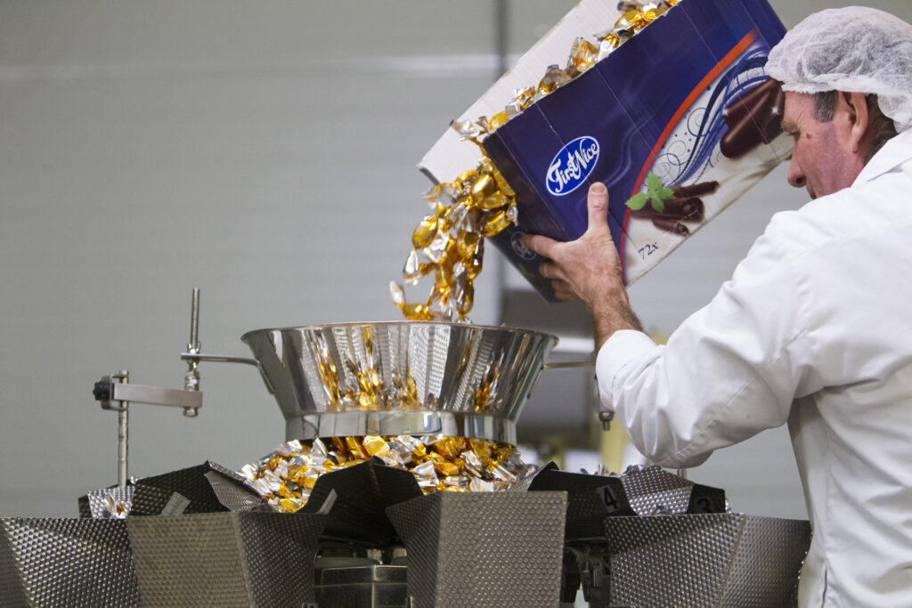 Karamellás szaloncukrot töltenek az adagológépbe egy keszthelyi üzemben (MTI Fotó: Varga György)