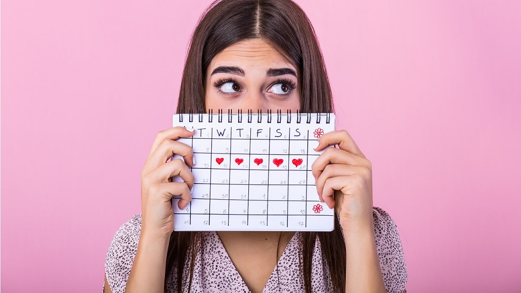 Fiatal nő menstruációs naptárral a kezében