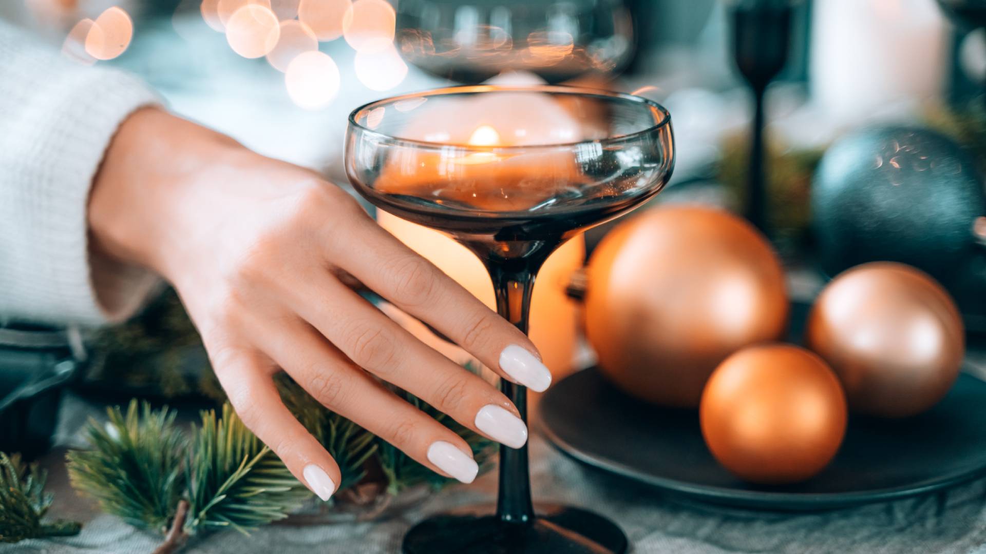 Fehér körmös kéz nyúl egy pohárért.