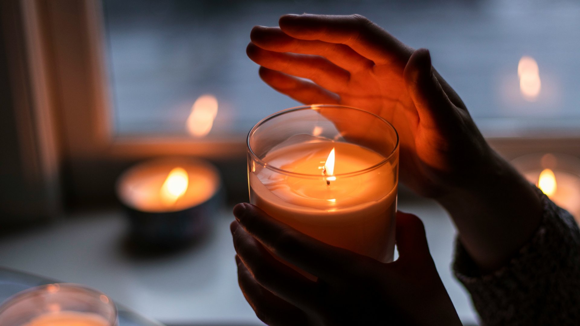 Kézben tartott meggyújtott gyertya.