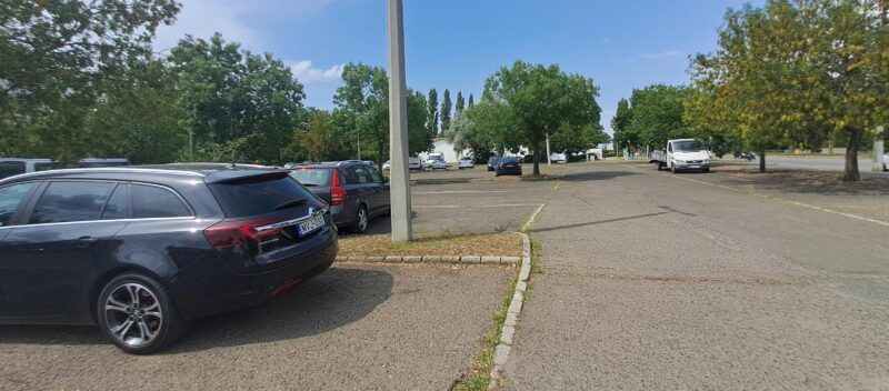 Napközben már félig tele a lakótelepi parkoló, távolban (a fák között a fehér épület) a leendő MERE - Fotó: F.C. / nlc