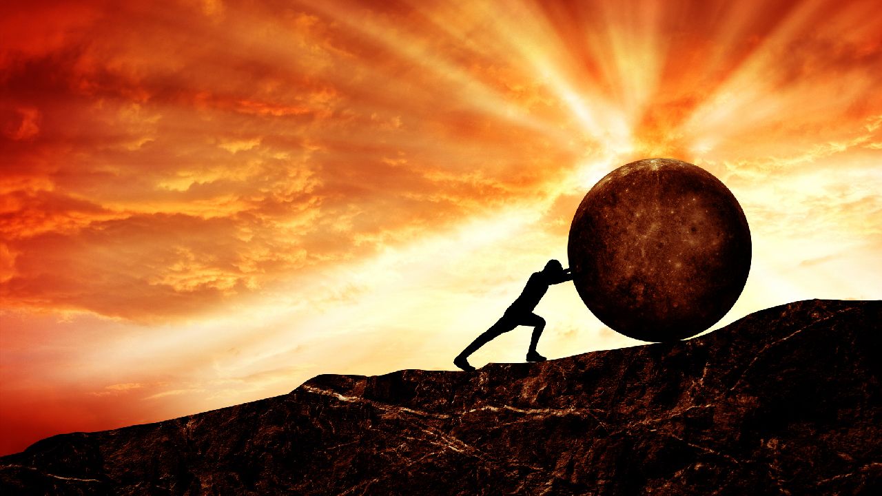 Férfialak gömböt görget felfelé a hegyre