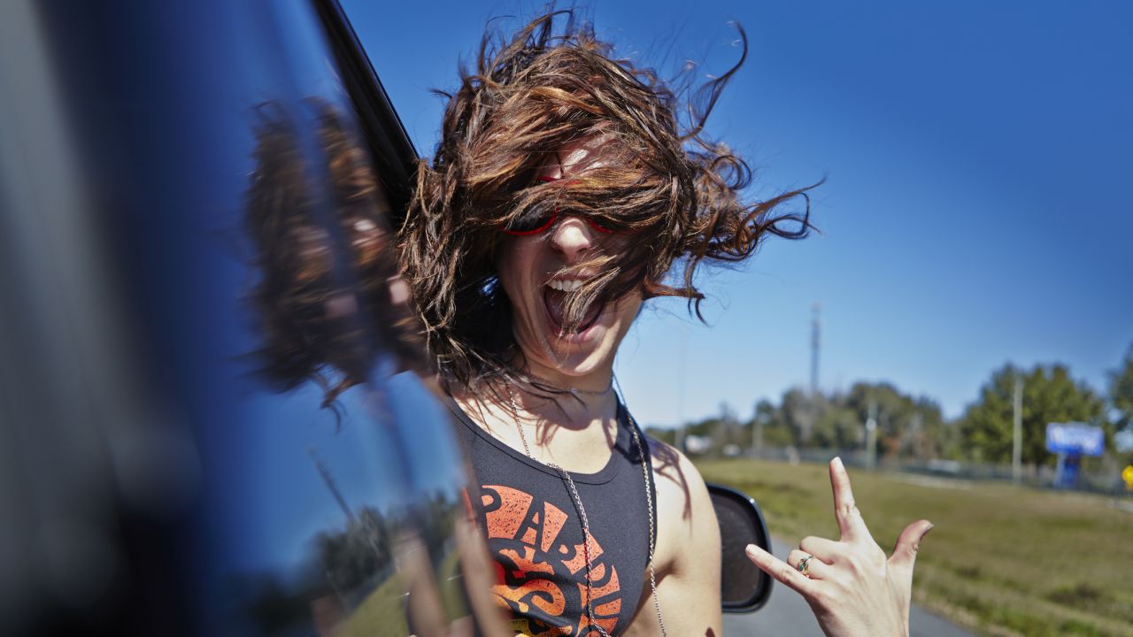 Lány nevetve kinéz az autóból