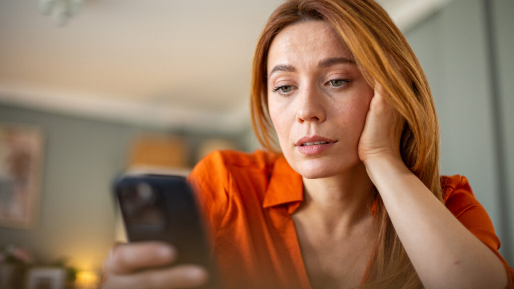 Kiábrándult nő telefonját olvassa